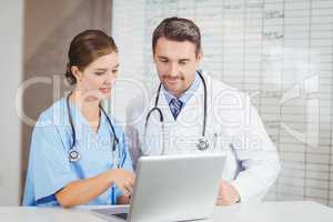 Doctor and colleague working on laptop while discussing