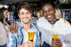 Smiling friends showing beer with their friends