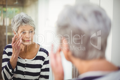 Reflection of senior woman looking at skin in mirror