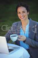 Pretty businesswoman having coffee and using laptop