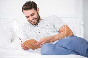 Man reading book on bed