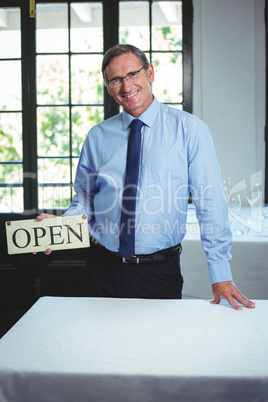 Smiling businessman holding open sign