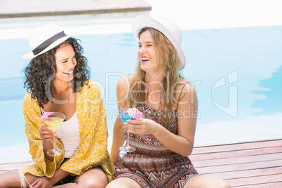 Young women having martini near pool