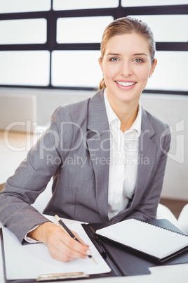 Young businesswoman with documents sitting at desk