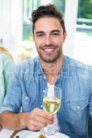 Portrait of happy man holding white wine glass