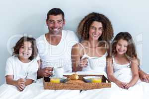 Portrait of a family sitting with breakfast tray in bed