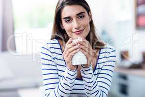 Portrait of beautiful young woman holding mug at home