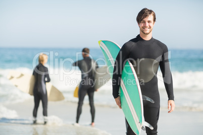 Portrait of happy man holding a surfboard on the beach