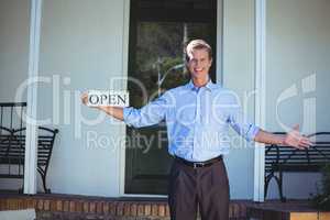 Handsome businessman holding an open sign