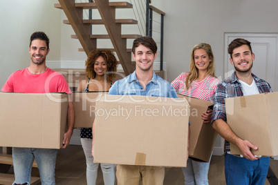 Friends smiling while carrying cardboard boxes