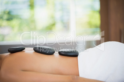 Woman lying on with stones on her back at spa