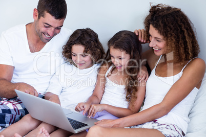 Family using laptop together on bed