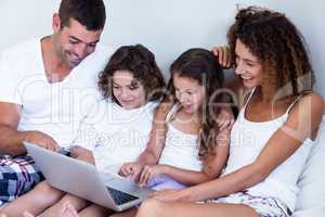 Family using laptop together on bed