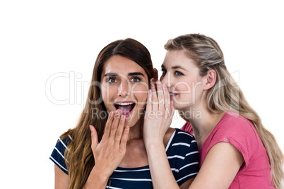 Smiling woman whispering in friend ear