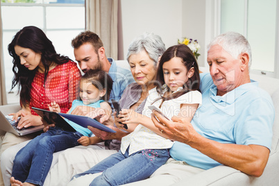 Family using technologies while sitting on sofa