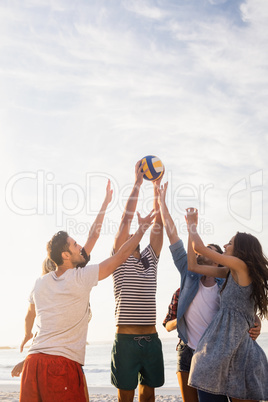 Happy friends playing beach volleyball