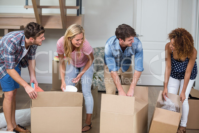 Friends unpacking carton in new house