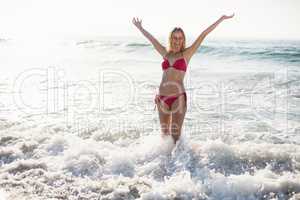 Excited woman in bikini standing on the beach