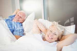 Portrait of happy senior woman relaxing besides man on bed