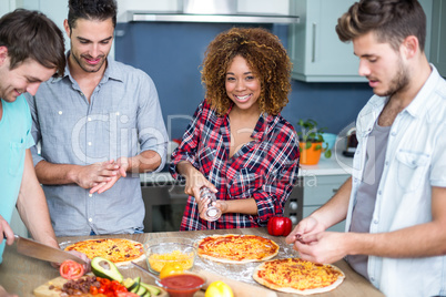 Young woman preparing pizza with friends on table