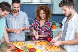 Young woman preparing pizza with friends on table