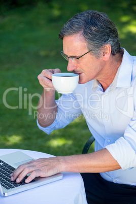 Casual businessman using laptop and having coffee