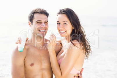 Portrait of happy woman applying moisturizer on mans nose