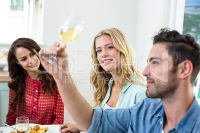 Man with friends looking at white wine glass