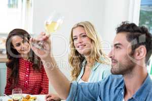 Man with friends looking at white wine glass
