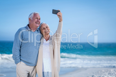 Cute mature couple taking selfie on the beach