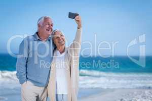 Cute mature couple taking selfie on the beach