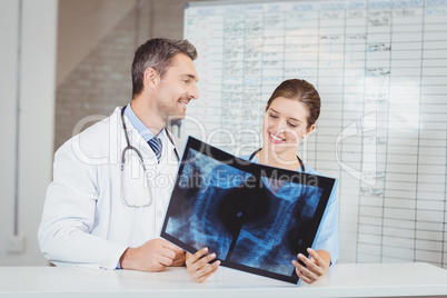 Happy doctors examining X-ray by chart