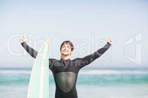 Happy man with surfboard standing on the beach