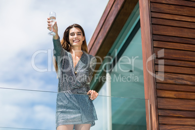 Gorgeuos woman showing champagne flute at balcony