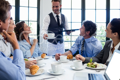 Waiter serving coffee to business people