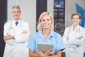 Portrait of cheerful doctor holding digital tablet while colleag