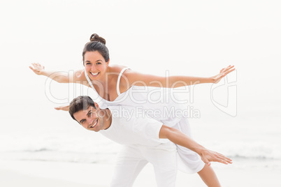 Man giving a piggy back to woman on the beach