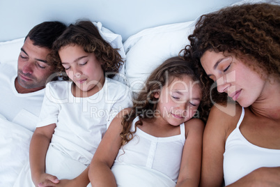 Family sleeping together on bed