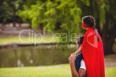 Girl in superhero costume sitting on fathers shoulders
