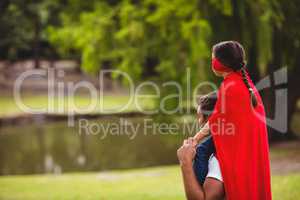 Girl in superhero costume sitting on fathers shoulders