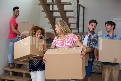 Friends carrying cardboard boxes in new house