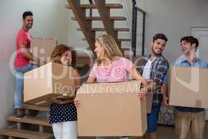 Friends carrying cardboard boxes in new house