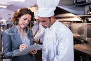 Female restaurant manager writing on clipboard while interacting