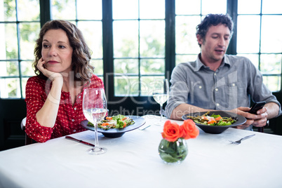 Woman feeling bored while man using his phone