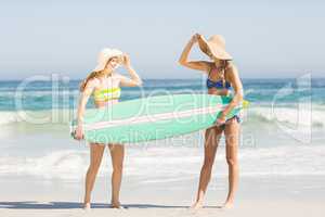 Two women holding a surfboard on the beach