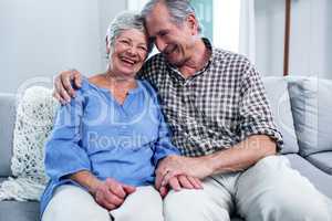 Happy senior couple sitting on sofa and embracing