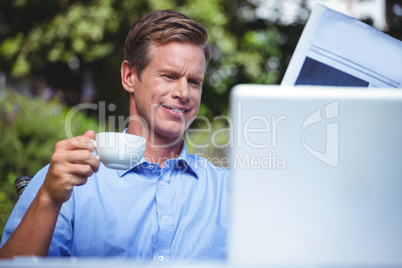 Handsome businessman having coffee and reading the news