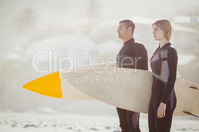 Couple with surfboard standing on the beach