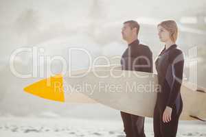 Couple with surfboard standing on the beach