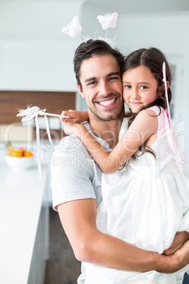 Portrait of father carrying daughter in fairy costume